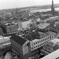 Utsikt mot sydväst från det första nybyggda höghuset vid Hötorget. Konstfackskolans lanternin på Mäster Samuelsgatan 44. Vid Klarabergsgatan schaktar man för tunnelbanan.