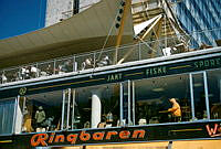 Sergelgatan 22. Skyltfönster till Friluftsaffär samt Ringbarens uteservering på takterrassen under en segelbaldakin.