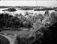 Vy norrut över området med Hägerstens gård och trädgård. I fonden  öarna Rotholmen och Lindholmen samt Smedslätten och Stora Essingen. Till höger delar av Vinterviken, Mörtviken och Ekensberg.