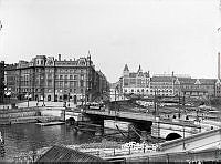 Vy över kungsbron mot kungsholmen med fleminggatan mitt i bilden.  En spårvagn och några människor på bron.