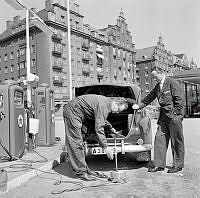 En man får sitt reservdäck i bakluckan på bilen påfyllt med luft på en bensinmack vid Norr Mälarstrand.