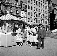 Människor framför en glasskiosk vid Norrmalmstorg.