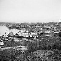 Vy från Henriksdalsberget mot Skanstullsbron. Hammarbyhamnen och Hammarby sjö. Båtar och fabriker.  