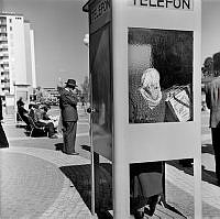 Vällingby centrum. En kvinna ringer i en telefonkiosk.