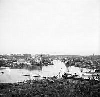 Vy från Henriksdalsberget. Hammarbyhamnen och Hammarby sjö. Båtar och fabriker. 