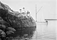 Några barn på en udde. Segelbåt.