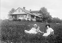 Två kvinnor och ett barn ligger i gräset framför Isola Bella.