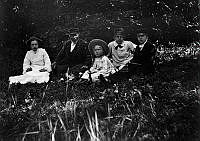 Fem personer sitter i en grässlänt.