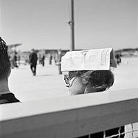 Bromma flygfält. Kvinna som har tidning på huvudet som skydd mot solen.