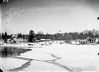 Vy mot land från isen. Telegrafhuset, Konditoriet,  Affären och Tullis. Lindholms hus med jordkällare och kvarn.