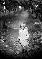 En liten flicka (kanske Dagny Johansson) på en väg med en blombukett.