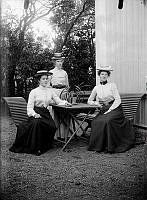 Tre kvinnor utomhus med en Mönjelilja på bordet.