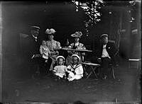 Gruppbild vid ett kaffebord utomhus. Två kvinnor, två män och två barn.
