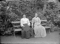 Två damer sitter på en bänk.