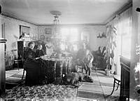 Interiör. Gruppbild på en kvinna, en man två pojkar och en hund i ett rum.