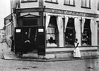 K.G. Markströms Guldsmedsaffär och Handelsbod i Norrtälje med allehanda varor. Två kvinnor står utanför affären.