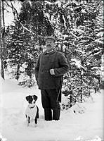 Hjalmar Öhman med gevär på axeln och hunden Roy.