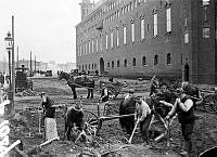 Män med hästar och kärror i arbete framför Stadshuset.