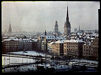 Skymningsbild över Gamla Stan med snö på taken.