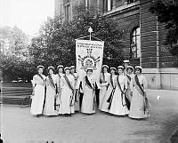 Deltagare vid den internationella kvinnliga rösträttskongressen i Stockholm år 1911 uppställda med standar vid Södra Blasieholmshamnen.