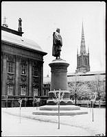 John Börjessons staty över Axel Oxenstiernas norr om Riddarhuset, i trädgården vintertid. I bakgrunden Riddarholmskyrkan.