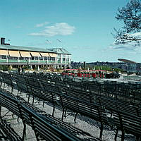 Skansen; vy från parkbänkarna vid Sollidenscenen mot Sollidens restaurang. Skansentåget åker förbi.