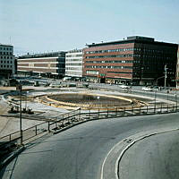 Vy från Malmskillnadsgatan mot varuhusen Åhlens och EPA. Fontänen vid Sergels Torg under uppbyggnad med armeringsjärn och gjutformar.