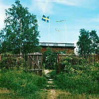 Öppen grind i staketet kring Borgen på Gärdet. Vy rakt mot västra fasaden.