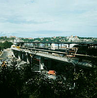 Vy från naturområde NO om Dianavägen i Hjorthagen mot Ropstens tunnelbanestation cirka två veckor före öppnandet. Stationen öppnades 2/9 1967. I fonden Lidingö.