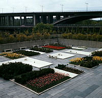 Dammar och blomsterrabatter i Folksam-husets gårdspark. Vy mot Skanstullsbron.