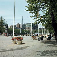 Kungsträdgården, planteringar och folkliv. Vy från parkens sydöstra del åt nordväst. I fonden Sverigehuset och Nordiska Kompaniet.