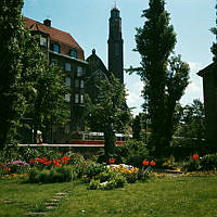 Borgarskolans park (nuv. Ellen Keys Park). Blommor planterade kring Sigrid Fridmans skulptur av Ellen Key. Vy mot Engelbrektskyrkan.