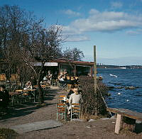 Djurgården; cafégäster på Blockhusuddens uteservering. Vy åt norr, i fonden Lidingö.