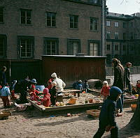 Barn och vuxna i sandlådan vid parkleken i Observatorielunden. I bakgrunden Handelshögskolan.