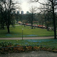 Första maj 1973. Vy från Floras kulle åt sydväst över Humlegården. Två demonstrationståg möts vid Linnéstatyn. I fonden Kungstornen.