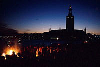 Valborgsmässoafton firas på Riddarholmen. Folksamling kring brasa. Vy mot Norr Mälarstrand och Stadshuset.