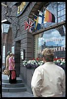 Skeppsbron 44. Restaurangen Zum Franziskaner. Människor utanför restaurangen. Blomsterplantering och nationsflaggor.