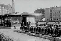 Väntsal för Roslagsbussarna och en kiosk vid Jarlaplan. I bakgrunden t.h. nybyggda Borgarskolan. Längst t.v. Karlavägen 11 och Engelbrektskyrkan.