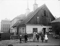 Fatburen. Gård på Värmdögatan 51, (senare Malmgårdsvägen). Barn står uppställda i förgrunden.