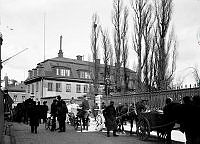 Västra Trädgårdsgatan med Lantmäterikontoret. Parkerade hästkärror, en häst äter ur havretornister. T.h. ligger Jakobs kyrkogård.