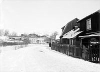 Trähusbebyggelse utanför Danvikstull. I fonden ses järnvägsviadukten med ångdrivet tåg.