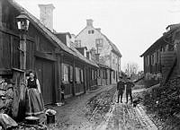 Stigbergsgatan österut. Hilma Borin hämtar vatten vid en vattenpost. Pojkarna ute i gatan är två av Hilmas fem barn, Helmer och John. T.h. Stigbergsgatan 36, platsen för blivande Navigationsskolan.
