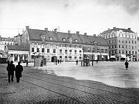 Hötorgets östra sida. Hötorget 14 och 12. T.h. mynnar Oxtorgsgatan. Tv. i fonden ligger Stora Bastugatan. Nuv. platsen för Konserthuset och 1:a höghuset vid Sergelgatan.