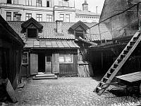 Gårdssidan av Smålandsgatan 17 i hörnet av Regeringsgatan. Huset revs 1904. Gatan är igenlagd och här ligger idag NK-varuhuset.