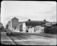 Roslagsgatan norrut mot korsningen med Surbrunnsgatan. Närmast t.h. kv. Målaren. På andra sidan Surbrunnsgatan ligger kv. Väduren med det gamla värdshuset Clas på Hörnet.