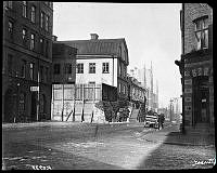 Roslagsgatan norrut från hörnet av Ingemarsgatan. Stenhuset bakom planket är värdshuset Lilla Ingemarshof, som revs i maj 1904.  En leverans från Münchens öl har just anlänt.