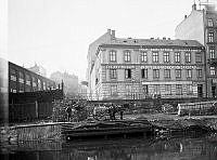 Utsikt från Gamla Kungsholmsbrogatan västerut mot Kungsholmsgatan 2 och Kungsbroplan 1. T.v. AB Bolinders maskinhallar. T.h. cigarrfabrik, snickeriverkstad samt rullgardinsfabrik. Nu Kungsbro Strand.