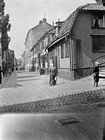 En kvinna går Tavastgatan västerut från Timmermansgatan. T.h. Tavastgatan 30-34. Tavastgatan 32, lumpaffären, revs 1910.