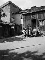 En grupp barn står på gårdssidan av Tavastgatan 55 mot norr. Husen t.v. ligger mot Stora Hargränd. Dåvarande kv. Haren Större. Nu kv. Haren söder om Gamla Lundagatan.