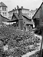 En man och två barn står på gårdssidan av Bengt Ekehjelmsgatan 16. Husen i fonden ligger vid Högbergsgatan 72-70. Den här delen av Bengt Ekehjelmsgatan är nu igenlagd och ingår i kv. Hållkarlen.